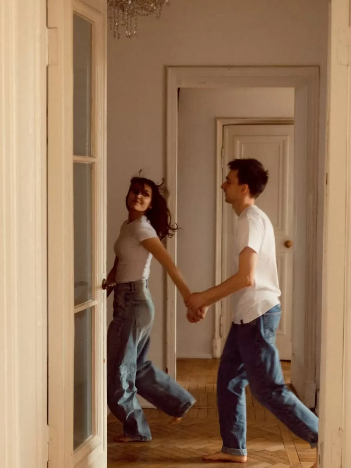 Couple holding hands, walking through a sunlit hallway