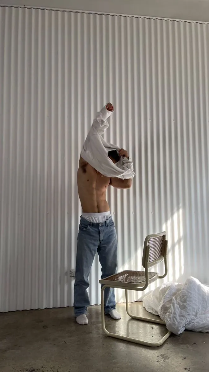 Man pulling off his shirt, wearing white Majella underwear