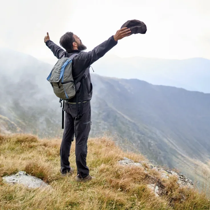 Man on a mountain ridge raising his arms
